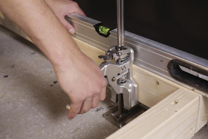 Ein Mann montiert einen Hängeschrank mit einer Wasserwaage und einem Montageständer an einer Wand.