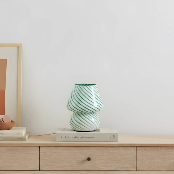 Dekorative Tischleuchte mit grün-weissen Streifen auf einem Nachttisch