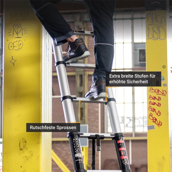 Person auf einer silbernen Teleskopleiter mit extra breiten, rutschfesten Stufen in einem industriellen Bereich.