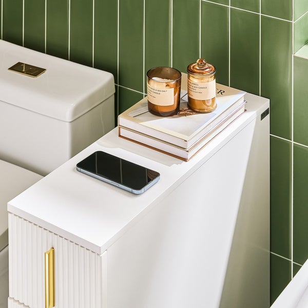 Detailansicht eines Badezimmers mit Toilette, Waschtisch, Dekoration und Smartphone.