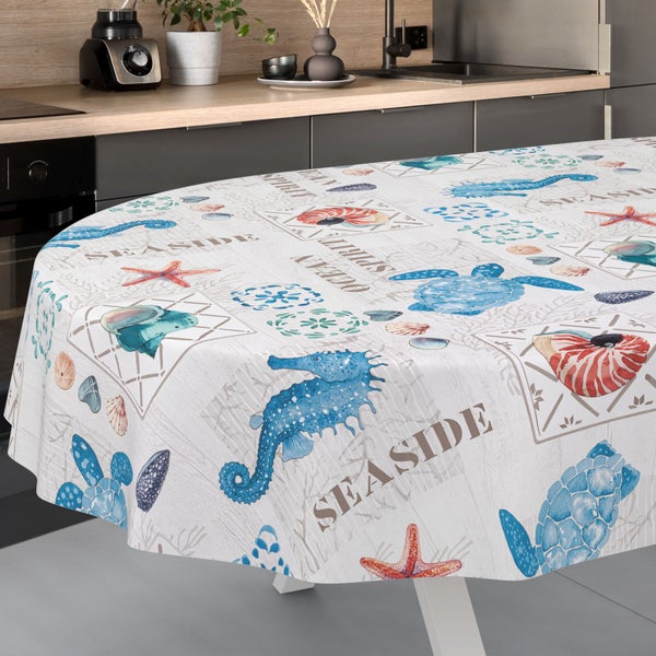 Runde Wachstuchtischdecke mit maritimem Muster aus Seepferdchen, Schildkröten und Seesternen auf einem Tisch in einer Küche.