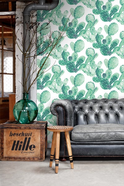 Wohnzimmer mit Kaktusmuster-Tapete, Ledersofa und Holzhocker