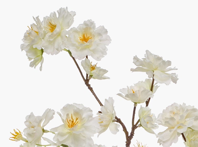 Künstlicher Zweig mit weißen Blüten und gelben Staubgefäßen.