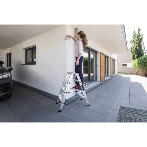 Frau auf einer Klappleiter, die an einem Bewegungsmelder arbeitet