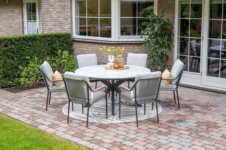 Modernes Gartenmöbel Set mit rundem Tisch und sechs Sesseln mit Seilbespannung auf einer hellen, organisierten Terrasse mit Pflanzen.