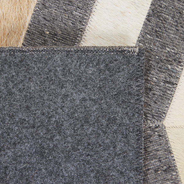 Detail eines Patchwork-Teppichs aus Kuhfell und Filz mit Zickzack-Nähten.
