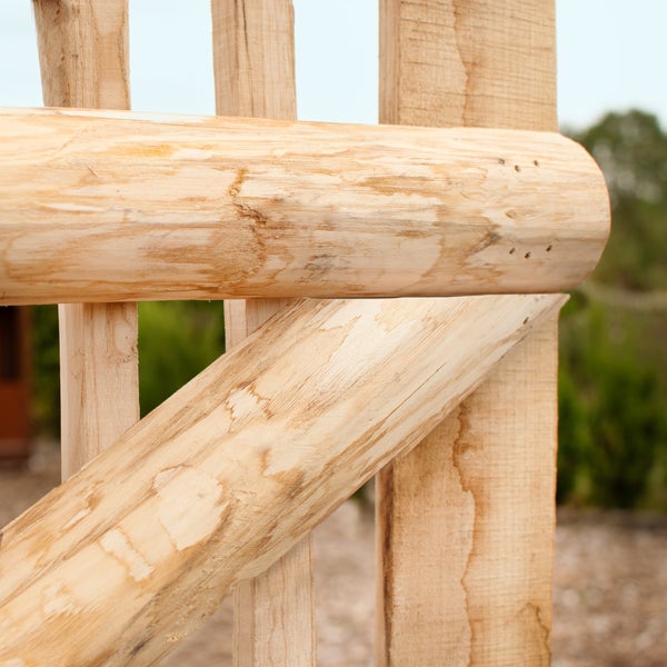 Detailansicht eines Holzzauns mit runden und eckigen Latten