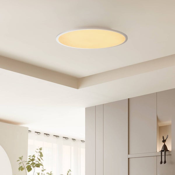 Runde LED-Deckenleuchte mit weißem Rahmen und warmem Licht an einer weißen Decke in einem hellen, modernen Raum mit Wandpaneelen.