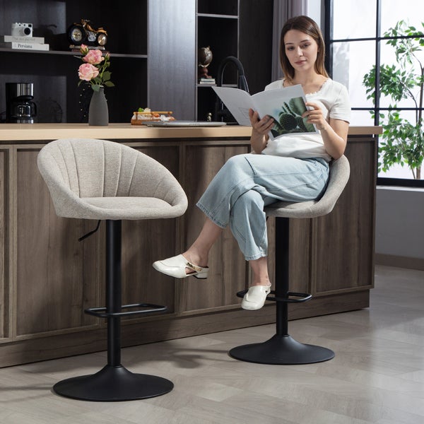 Moderne Barhocker mit gepolsterten Sitzschalen und höhenverstellbaren Metallgestellen an einer Kücheninsel, eine Person sitzt lesend auf einem Hocker.