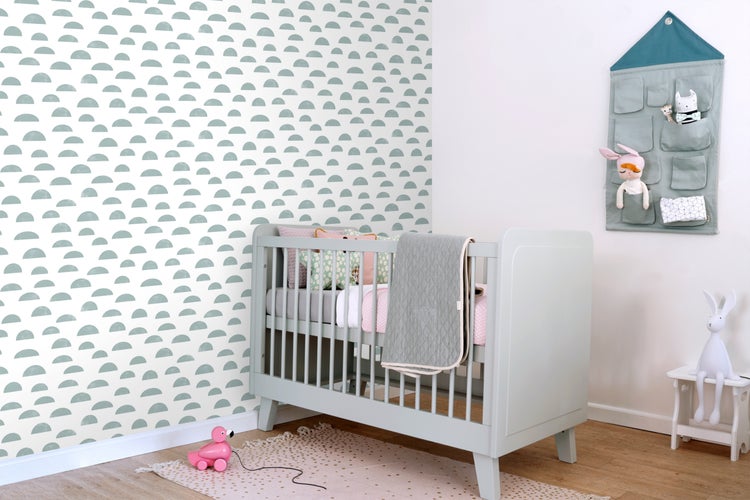 Helles Kinderzimmer mit Babybett, Wandaufbewahrung und dekorativer Wandgestaltung