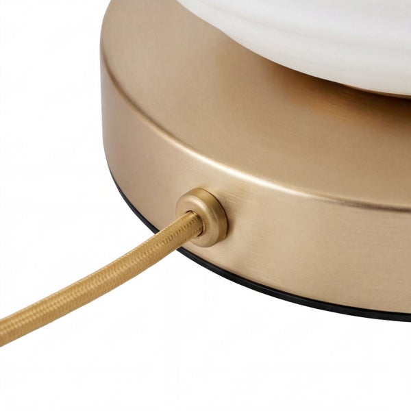 Detailansicht eines runden Lampenfußes aus gebürstetem Metall mit textilumwickeltem Kabel.