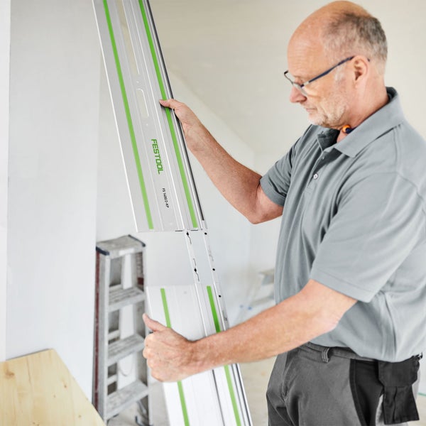 Handwerker verbindet zwei Festool Führungsschienen FS 1400/2-KP in einem hellen Innenraum.