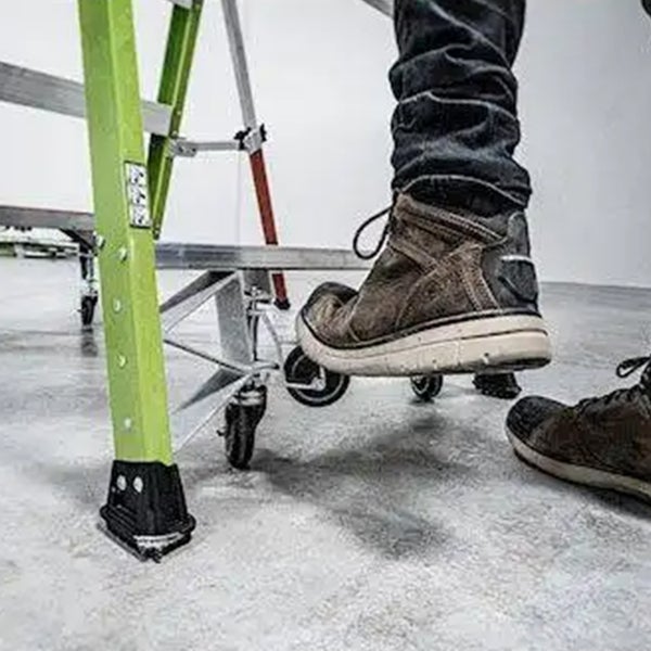 Nahaufnahme einer Person in Arbeitsschuhen, die eine Leiter mit Rollen betritt.