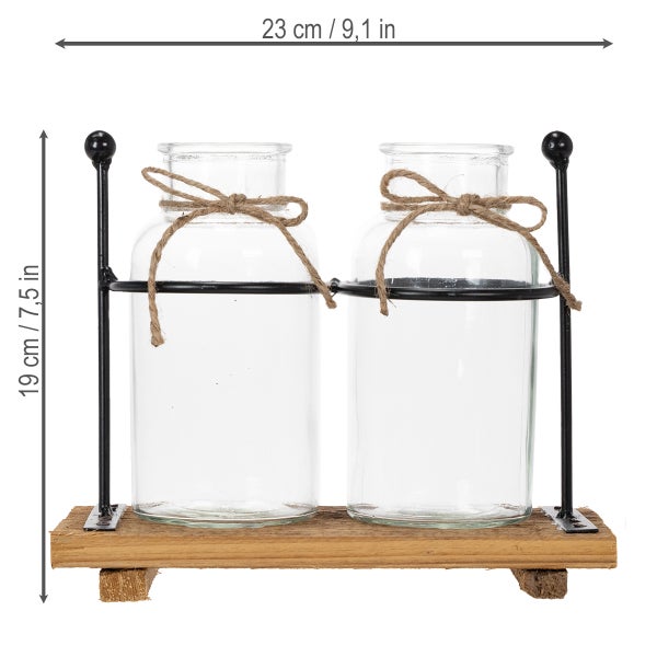 Zwei Dekoflaschen aus Glas auf einem Holzsockel mit schwarzem Metallgestell und Jutebändern. Breite 23 Zentimeter, Höhe 19 Zentimeter.