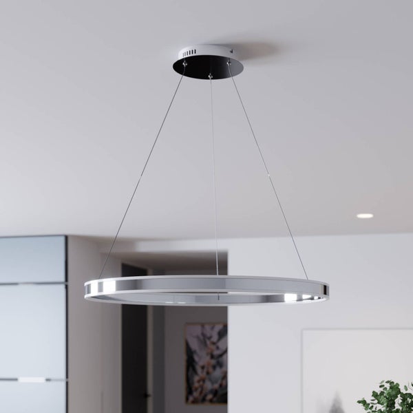 Moderne ringförmige LED-Pendelleuchte in Chrom-Optik, hängend an drei dünnen Drahtseilen in einem hellen, modern eingerichteten Raum.