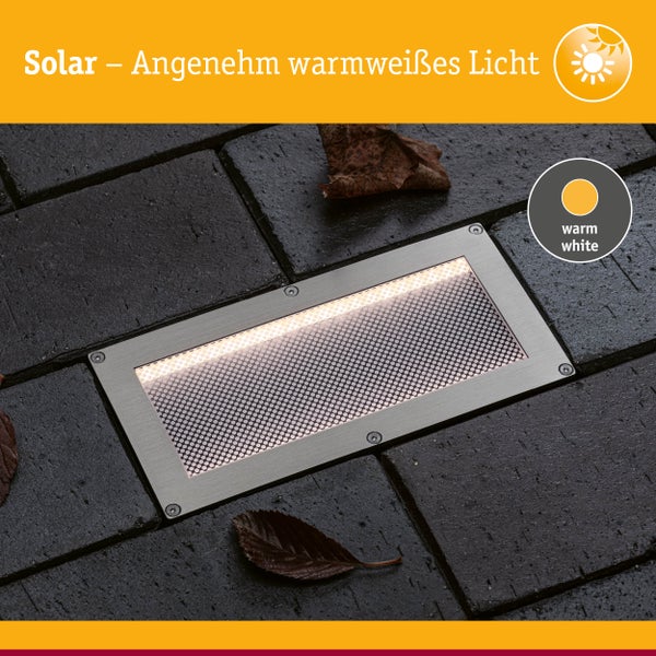 Solarbetriebene rechteckige Bodeneinbauleuchte aus Edelstahl mit warmweißem Licht, eingebaut in Pflastersteinen.
