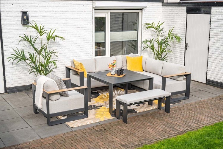 Modernes Gartenmöbel-Set mit Ecksofa, Sessel, Bank und Esstisch. Gestell aus dunklem Metall mit Holzdetails und hellgrauen Polstern auf Terrasse.