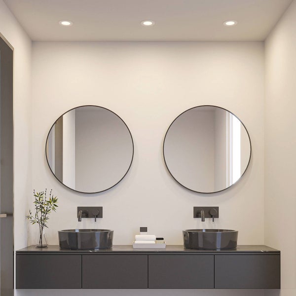 Modernes Badezimmer mit zwei runden Spiegeln, dunklen Aufsatzwaschbecken und schwarzen Wandarmaturen auf einem schwebenden Unterschrank.