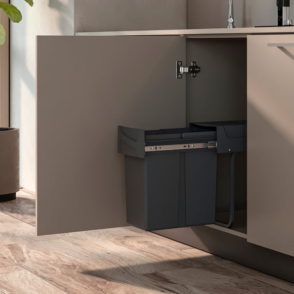 Ausziehbarer Abfalleimer montiert in einem Küchenunterschrank mit geöffneter Tür auf einem Holzboden.