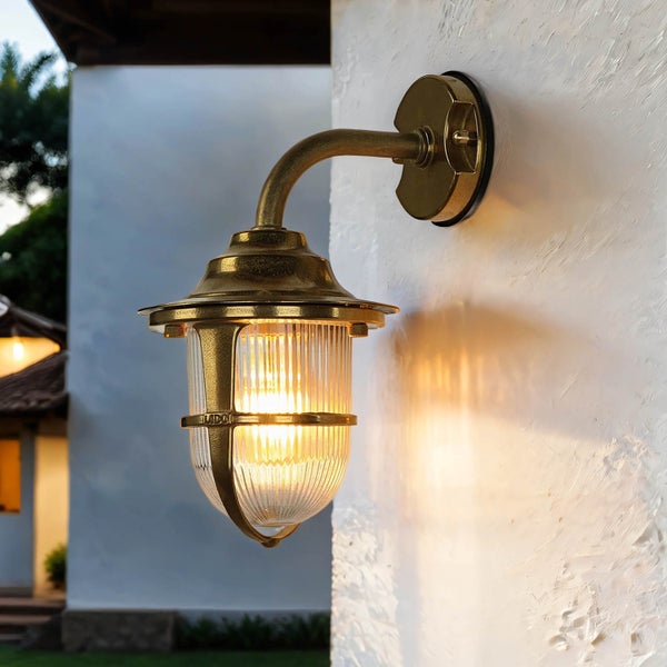 Goldene Aussenwandleuchte mit klarem, geriffeltem Glas auf weisser Wand