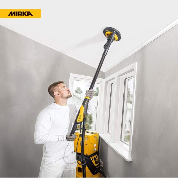 Ein Handwerker schleift mit einem Mirka Langhalsschleifer die Zimmerdecke ab, der an einen Baustaubsauger angeschlossen ist.