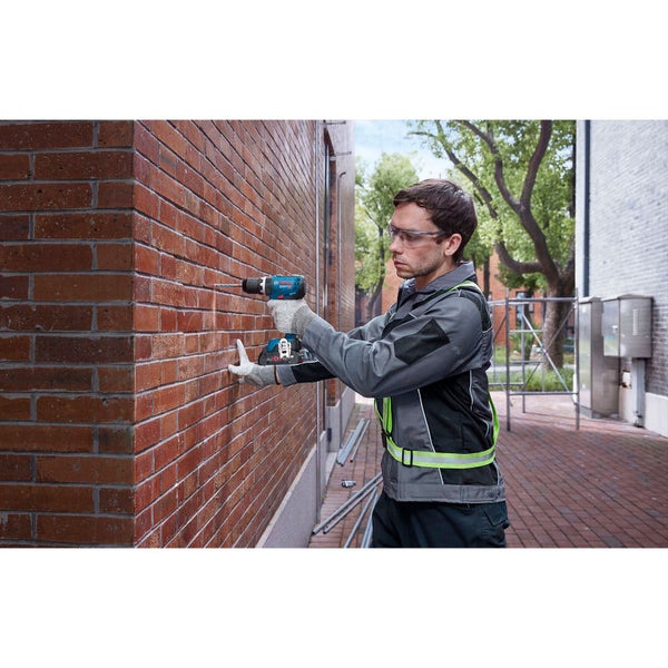 Handwerker bohrt mit einem Akku-Bohrschrauber Löcher in eine Decke für die Installation von Rohren