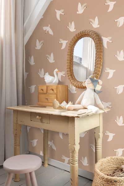 Kinderzimmer mit Tapete mit Vogelmotiv, Holztisch mit Dekorationen, Weidenkorb und Spiegel