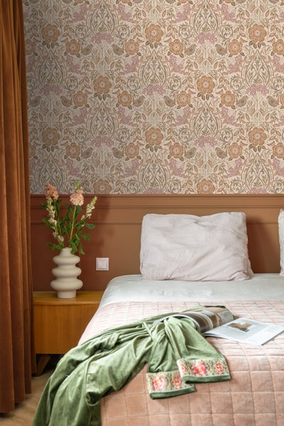 Schlafzimmer mit floral gemusterter Tapete, Bett und Nachttisch