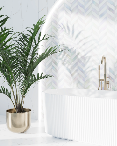 Modernes Badezimmer mit einer weißen, geriffelten freistehenden Badewanne, einer goldenen Armatur und einer Zimmerpflanze im goldenen Topf.