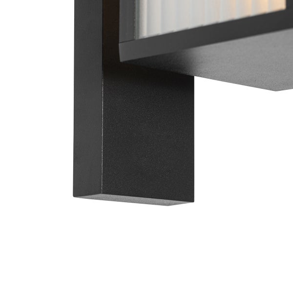 Nahaufnahme einer schwarzen Außenwandleuchte aus Metall mit geripptem Glaseinsatz.
