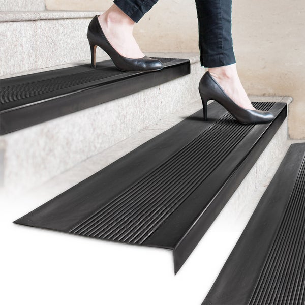 Treppenstufen mit Antirutschmatten und einer Frau mit hochhackigen Schuhen, die die Treppe hinaufgeht