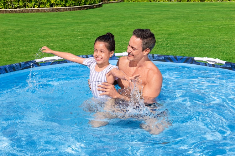 Mann und Kind spielen in einem gemusterten Aufstellpool mit Rahmen im Garten auf einer Rasenfläche.