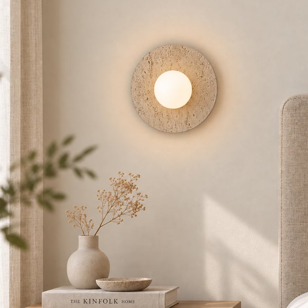 Moderne Wandleuchte mit rundem Travertinpanel und einer zentralen Lichtkugel zur stimmungsvollen Beleuchtung im Schlafzimmer.