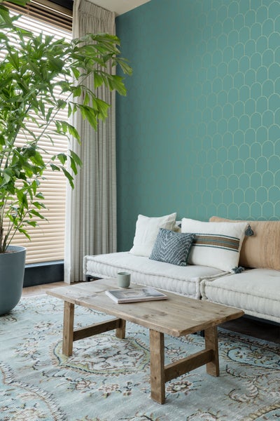Wohnzimmer mit grüner Tapete, Couch, Holztisch und Teppich