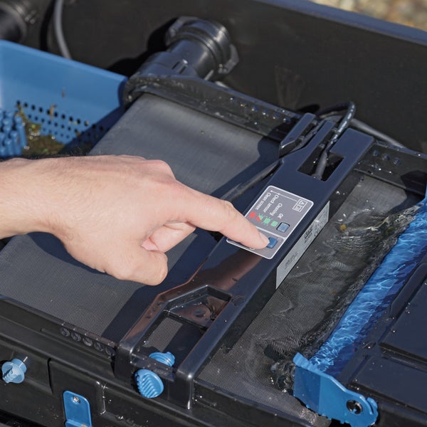 Hand betätigt Knopf am Bedienelement eines Teichfilters mit Filtersieb und Kontrollleuchten für Reinigung und Sensor.
