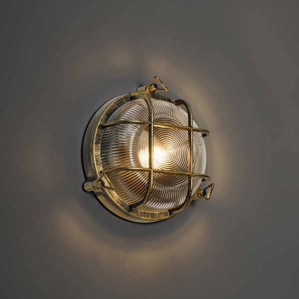 Runde Außenwandleuchte im nautischen Stil mit Metallgitter und geripptem Glas, eingeschaltet.