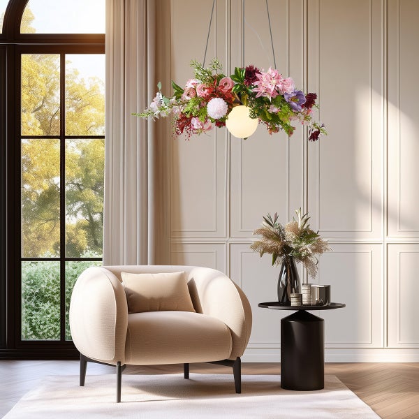 Helles Wohnzimmer mit beige gepolstertem Sessel, schwarzem Beistelltisch und einer Hängeleuchte, die mit bunten Kunstblumen verziert ist.