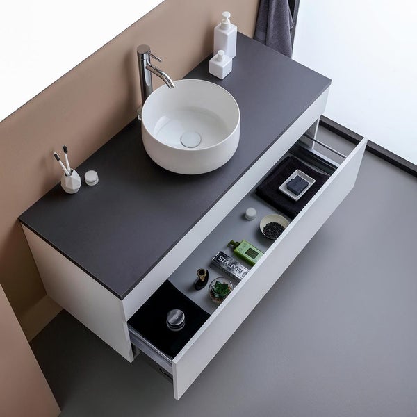 Modernes Badezimmerensemble mit Waschbecken, Armatur und offenem Schubladenelement für Badutensilien.