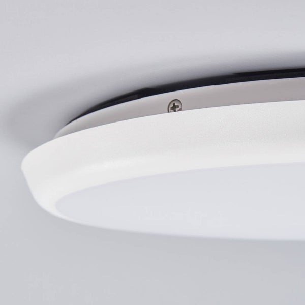 Nahaufnahme einer flachen, runden, weißen Deckenleuchte von der Seite mit sichtbarer Befestigungsschraube.