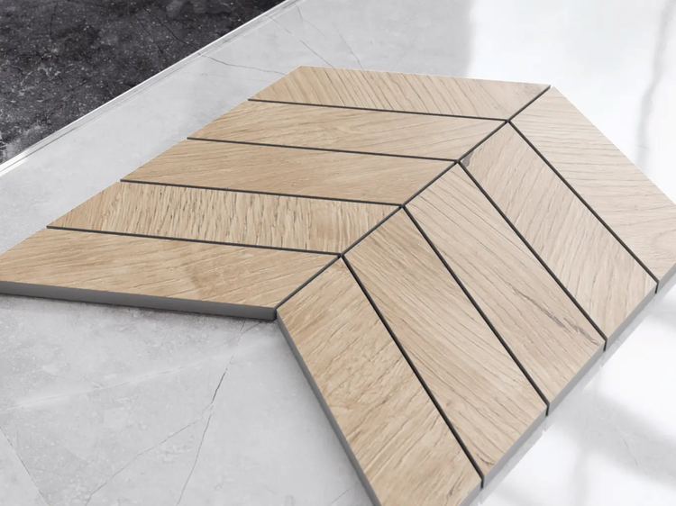 Mosaikfliese in Holzoptik mit Chevron-Muster auf einer Marmoroberfläche.
