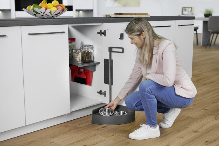Ausziehbarer Schrankorganisator für Haustierzubehör in einem weißen Küchenunterschrank mit Futternäpfen und Ablagefläche.