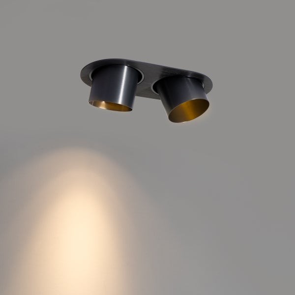 Zweiflammiger Deckenstrahler aus Metall mit zylindrischen Schirmen, dunkle Außenseite und goldfarbene Innenseite.