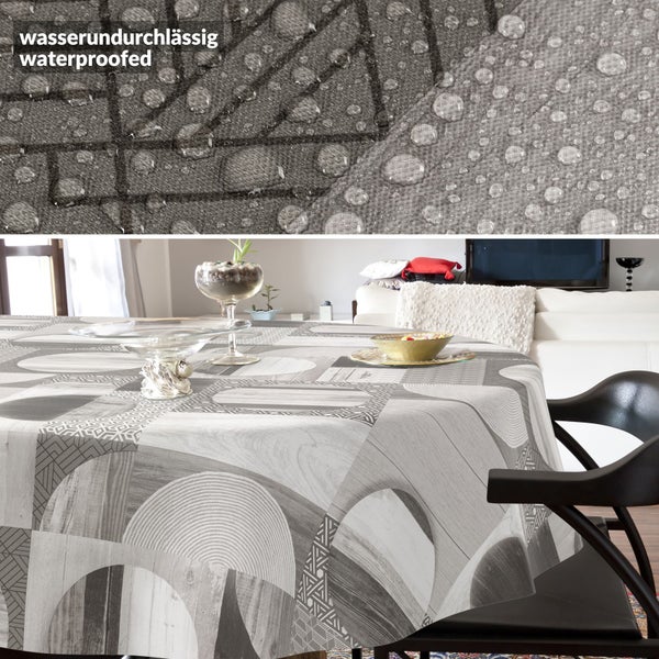 Wasserundurchlässige Tischdecke mit modernem geometrischem Muster auf einem runden Tisch in einem hellen Wohnzimmer.