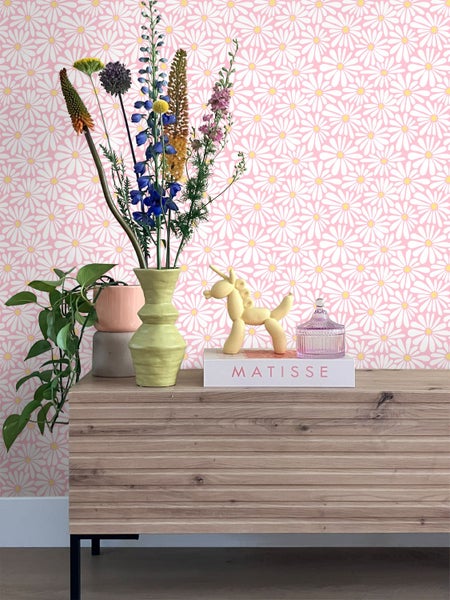 Dekoratives Zimmer mit gemusterten Tapeten, Kommode aus Holz und Blumenvase