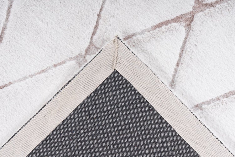 Nahaufnahme eines Kunstfellteppichs mit geometrischem Muster, die gewebte Rückseite und die eingefasste Ecke zeigt.