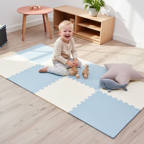 Kind spielt mit Holzbausteinen auf einer Puzzlematte aus Schaumstoff in einem hellen Zimmer mit Holzboden.