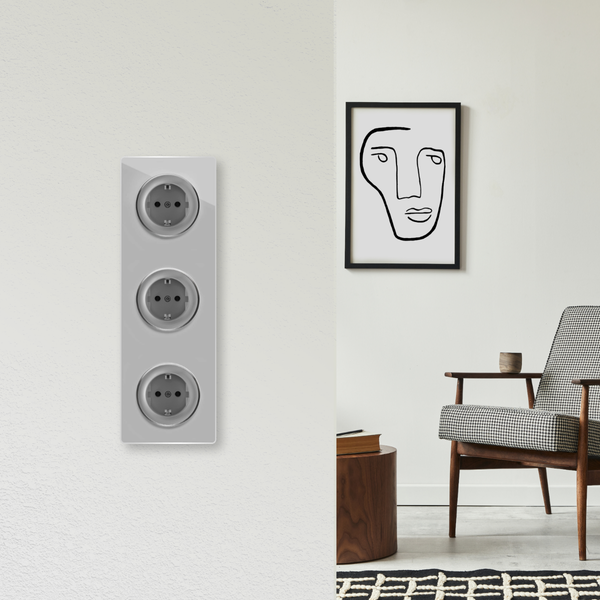 Dreifach Steckdose auf einer hellen Wand mit einem Wohnzimmer im Hintergrund.