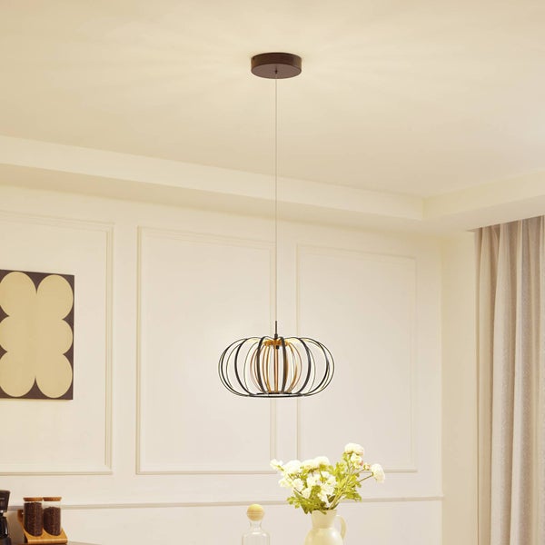 Moderne Pendelleuchte mit Metallkäfig in Schwarz und Gold, aufgehängt in einem hellen Raum über einem Tisch mit Blumen.