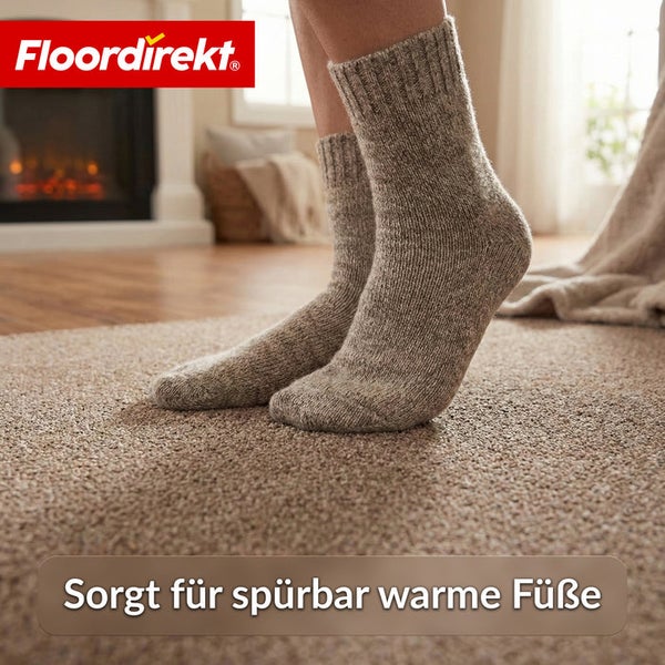 Eine Person mit Wollsocken auf einem Teppichboden vor einem Kamin. Floor direkt Logo.