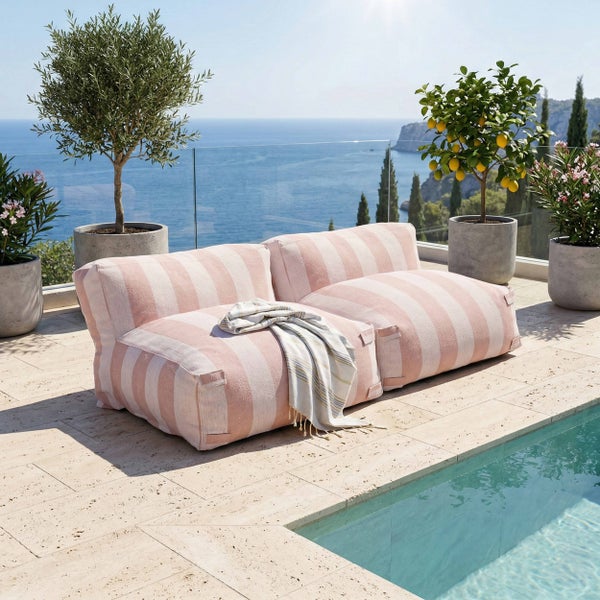 Helles Outdoor-Sitzsack-Sofa mit Streifenmuster auf einer Terrasse aus Naturstein neben einem Pool mit Blick auf das Meer.